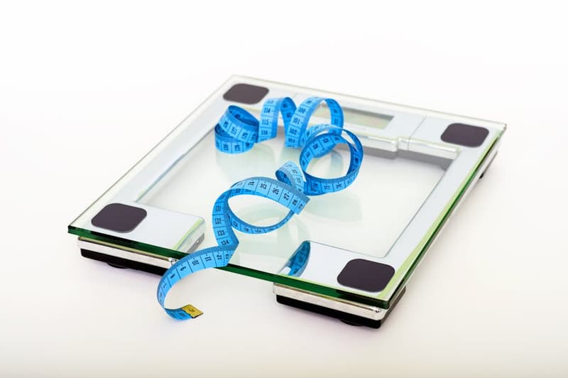 A person standing on a digital scale with a tape measure nearby